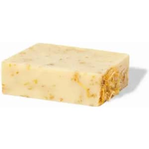 A bar of natural soap with a creamy yellow colour, featuring visible herbs and floral fragments embedded within.
