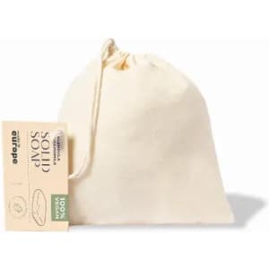 A drawstring pouch containing solid soap. The pouch is a natural cream colour and features a logo.