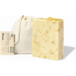 A natural shampoo bar with a creamy yellow hue and floral inclusions, accompanied by a small fabric pouch.