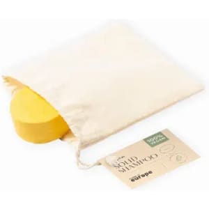A solid shampoo bar in a natural fabric pouch, featuring a circular yellow bar and a cardboard tag.