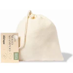 A drawstring bag containing solid shampoo, in a natural cream colour with a tag indicating it's 100% vegan.