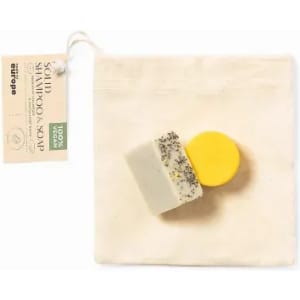 A solid shampoo soap in yellow and white, with a natural texture, packaged in a small fabric bag.