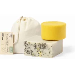 A set of solid shampoo and soap bars in yellow and creamy white, packaged with a natural fabric pouch.