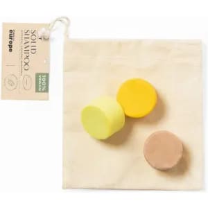 Three solid shampoo bars in yellow, green, and brown, presented in a natural fabric bag with a tag.