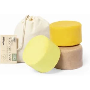 A set of solid shampoo soaps in yellow and brown, accompanied by a drawstring bag, featuring a brand logo.