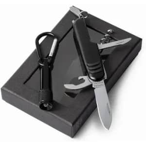 A black multi-tool knife sits on a black box, accompanied by a black carabiner. The knife features a silver blade and various tools.
