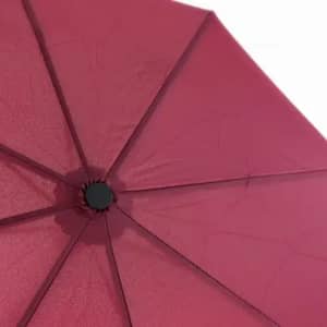 A maroon umbrella with a dark centre hub, showcasing the inner structure and fabric texture.