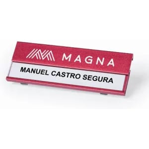 A name badge with a red background, featuring a logo and a white name plate for Manuel Castro Segura.