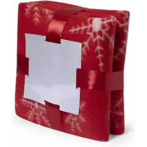 A wrapped gift in bright red fabric decorated with snowflakes, tied with a red ribbon and featuring a blank label.