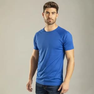 A blue T-shirt worn by a man standing against a plain background. The shirt features a simple design and a logo.