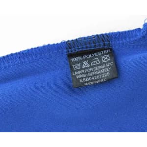 A close-up of a blue fabric with care label detailing material and washing instructions. The fabric is 100% polyester.