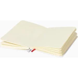 A notebook with a plain cream interior, featuring a red ribbon bookmark and soft cover.