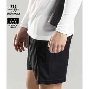 A pair of black sports shorts made from breathable, technical fabric, showcased with a hand holding a textured item.