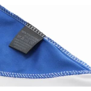 A blue and white fabric corner with visible stitching and a care label attached.