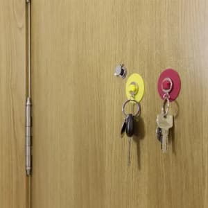A wooden door with two key holders, one yellow and one red, each holding keys.