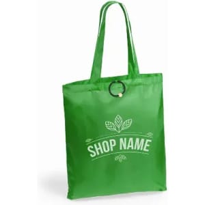 A green reusable shopping bag with a handle and a circular detail, featuring a logo and decorative leaves.