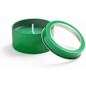 A green candle in a round metal tin, with the lid slightly opened. The candle has a white wick.