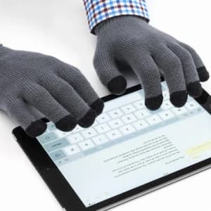 A pair of grey touchscreen gloves with black tips, being used on a tablet device.