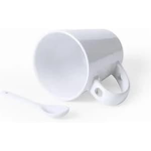 A white ceramic mug with a unique handle design and a matching spoon beside it.