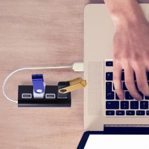 A USB hub featuring multiple ports in black with blue and gold accents, connected to a laptop.