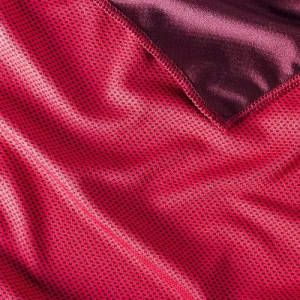 A close-up of textured fabric in shades of deep pink and burgundy, featuring a dotted pattern.