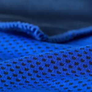 A close-up of blue fabric featuring a textured design with small black dots and a smooth surface.