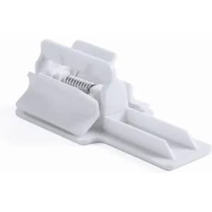 A white plastic product holder with a spring mechanism and a flat base. It features a simple, functional design.