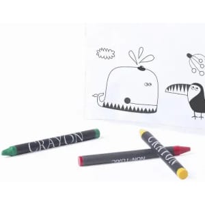 Three crayons in green, red, and black are placed beside a colouring sheet featuring a whale and a toucan.