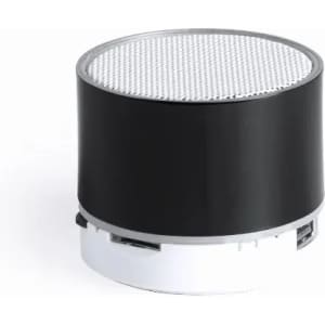 A compact black and white speaker with a circular design and a mesh top for sound output.