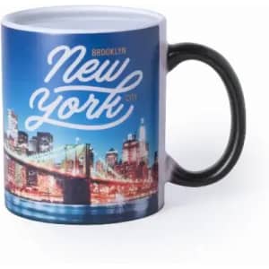 A coffee mug featuring a New York cityscape design with a black handle and colourful skyline at night.