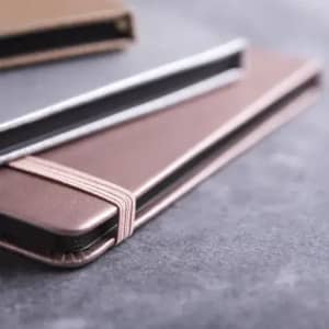 A selection of sleek, leather-like cardholders in shades of brown and grey, featuring elastic closures.