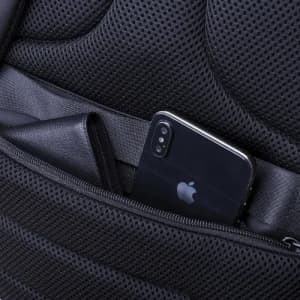 A black smartphone and wallet tucked into the pocket of a black, mesh-lined backpack.