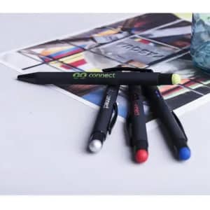 A collection of four pens in various colours—black, red, blue, and yellow—displayed on a colourful magazine page.