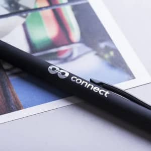 A black pen with a branding logo rests on a printed image, showcasing a colourful background.