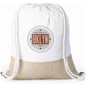 A drawstring bag in white with a hessian bottom and a circular logo featuring text about New York City.