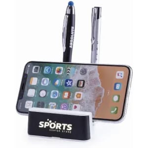 A phone stand featuring a black and white base, holding a smartphone and two pens, one black and one silver.