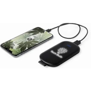A wireless charger with a black design, connected to a smartphone displaying green foliage on its screen.