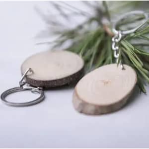 A wooden keychain featuring oval slices of wood attached to a metal ring and chain. Greenery in the background.