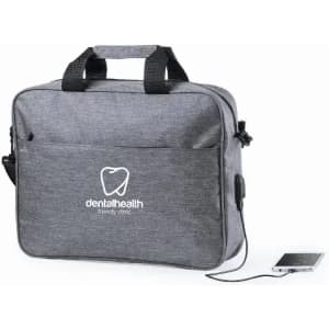 A grey bag with handles features a front pocket and a logo, with a connected device visible on the side.