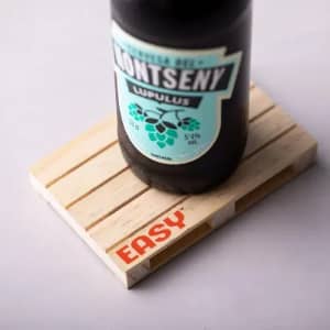 A drink bottle with a black body and turquoise label sits on a wooden coaster, featuring a logo.