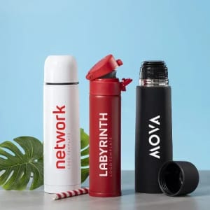 Three drink bottles in white, red, and black, featuring different designs and a tropical leaf in the foreground.