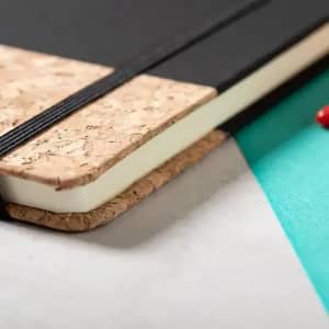 A notebook with a cork cover and black pages, featuring an elastic band for closure.
