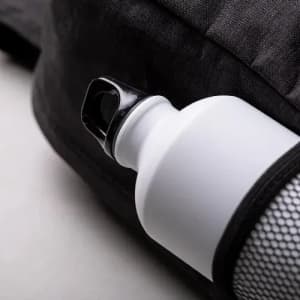 A drink bottle with a black lid and a white body, resting against a dark background. It features a logo.