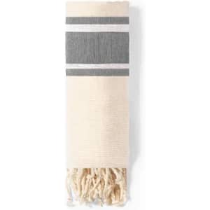 A woven towel in cream and grey, featuring striped patterns and fringed ends. It is neatly rolled.