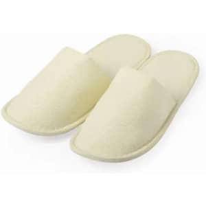 A pair of cream-coloured slippers, featuring a simple slip-on design with a soft, textured surface.