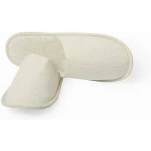 A pair of cream-coloured slippers made from textured fabric, featuring an open back design.