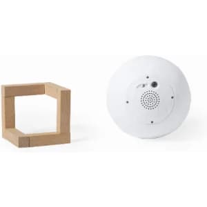 A wooden geometric shape and a round white speaker with a small logo.