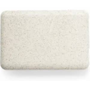 A bar of soap in a light beige colour with a speckled texture, featuring a rounded edges and a smooth surface.
