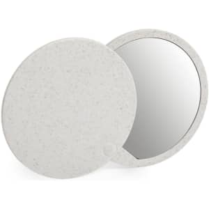 A compact mirror with a speckled white exterior, featuring a round design and a reflective surface.
