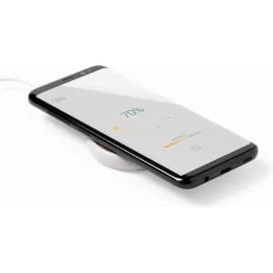 A wireless charging pad with a smartphone placed on it, indicating a battery charge of 75%. The charging pad is white.
